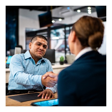 2 people shaking hands over a desk.